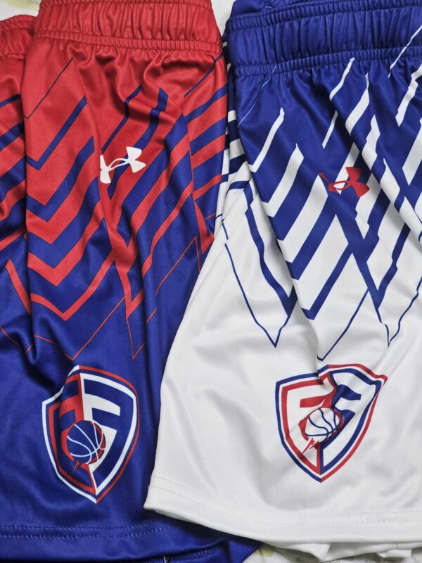 Flint's Finest UA Game Shorts in white and royal blue, side by side, featuring lightweight, moisture-wicking fabric with the brand logo on the right hem